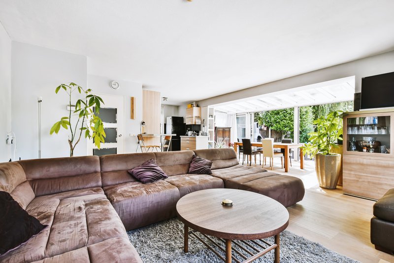 Sala abierta con sofá en forma de L, color gris, in neutro que resalta en casa.